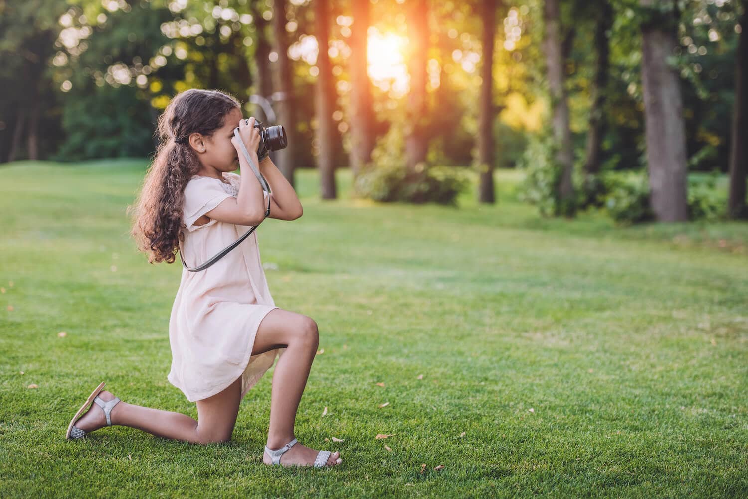 A girl in a pink dress is taking photos outdoors.