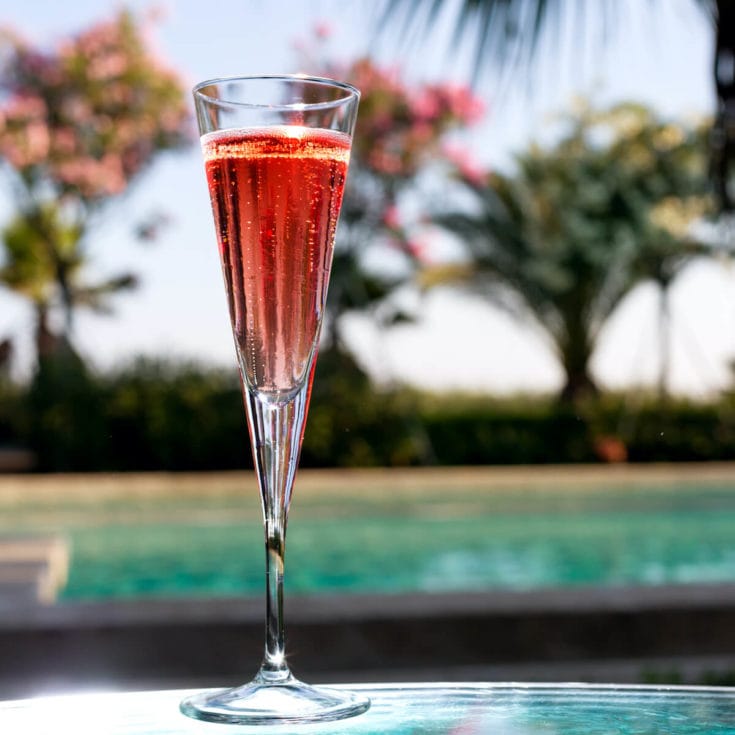 kir royal cocktail in a tall champange glass sitting by a swimming pool