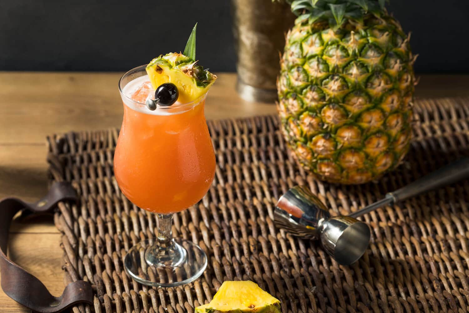 A fruity Singapore Sling cocktail in a tall glass with a pineapple garnish. 