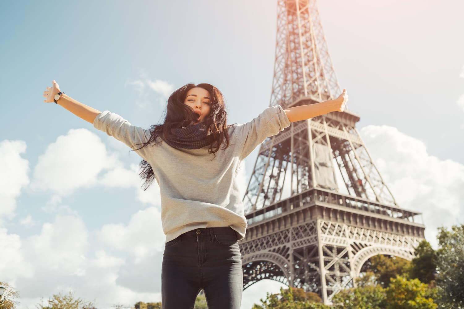 a young woman jumping with joy in front of the Eiffel Tower in Paris.