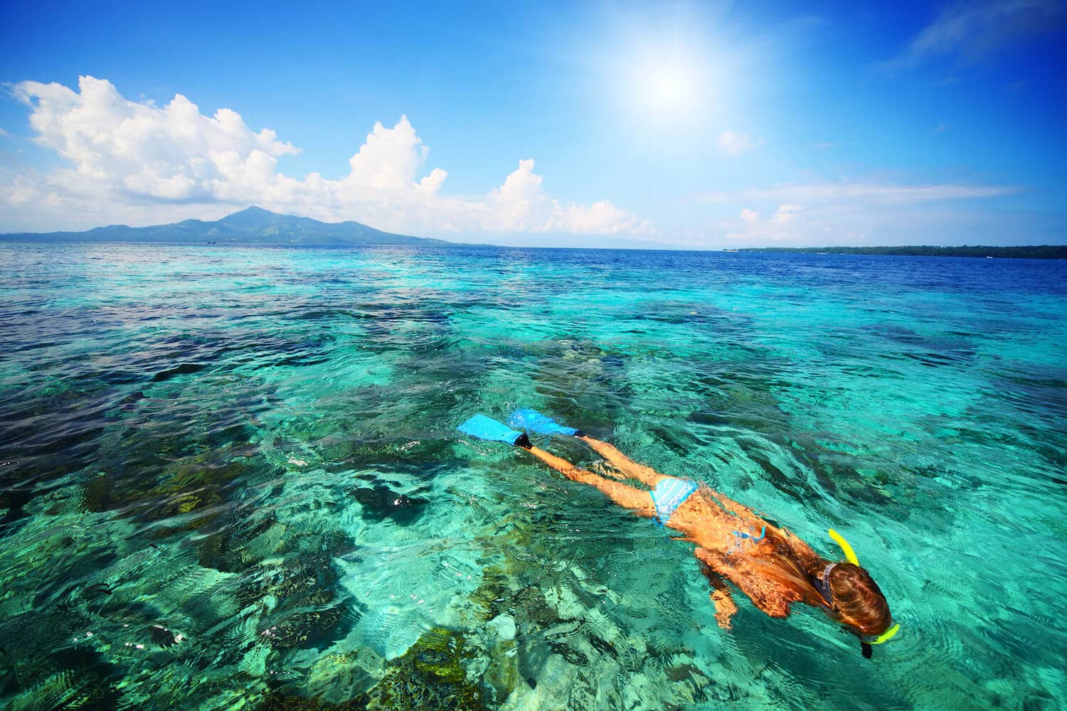 A woman snorkelling in the ocean over coral reef.
